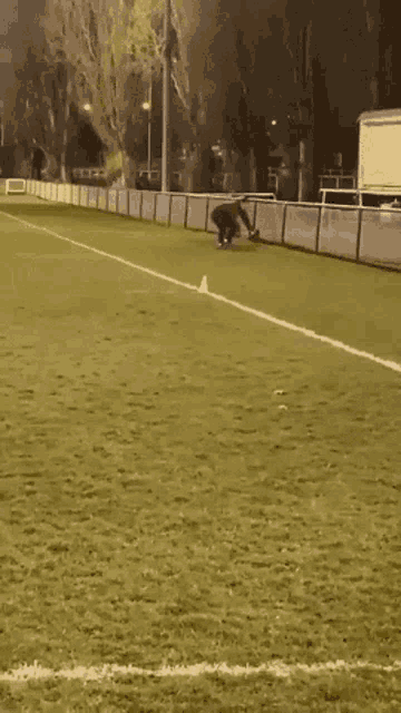 a person kneeling down on a soccer field with a yellow cone in the middle