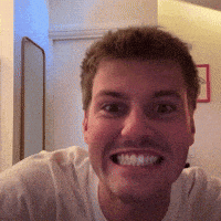 a man in a white shirt is smiling with his mouth wide open