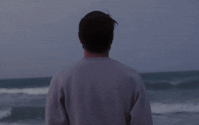 a man is standing in the water on the beach with a fire coming out of his back
