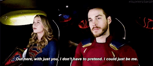 a man and a woman are sitting next to each other in a car and the man is wearing a superman costume .