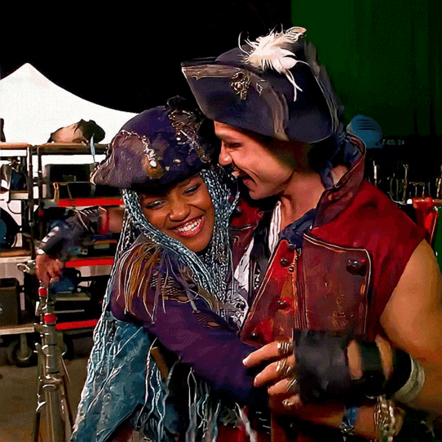 a woman in a pirate outfit is hugging a man in a pirate outfit