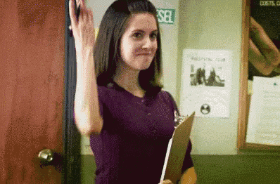 a woman in a purple shirt is holding a clipboard and giving a high five .