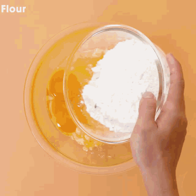 a person is pouring cocoa powder into a bowl of flour