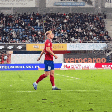a soccer player with the number 18 on his shorts is walking on the field
