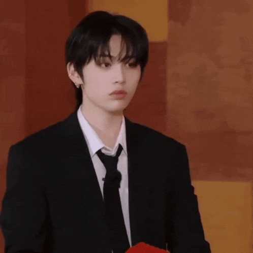 a young man in a suit and tie is standing in front of a wooden wall .