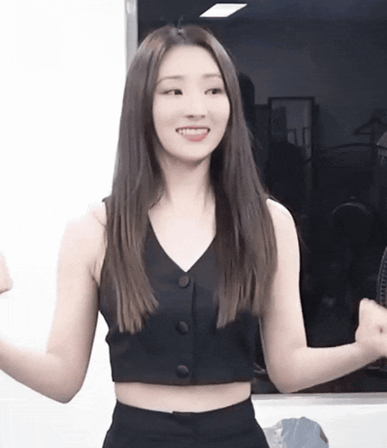 a woman wearing a black crop top and black pants is smiling