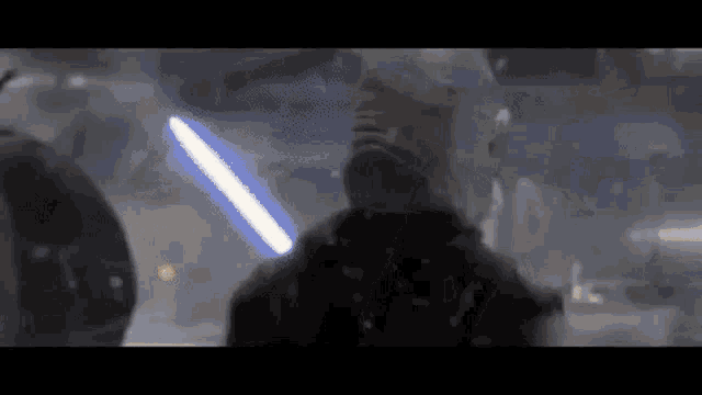 a man in a mask is holding a blue lightsaber in his hand .