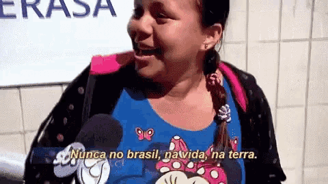 a woman wearing a minnie mouse shirt is talking into a microphone