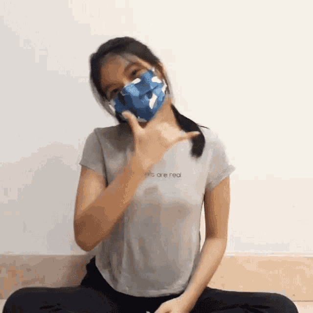 a girl wearing a mask and a t-shirt that says ' we are real '