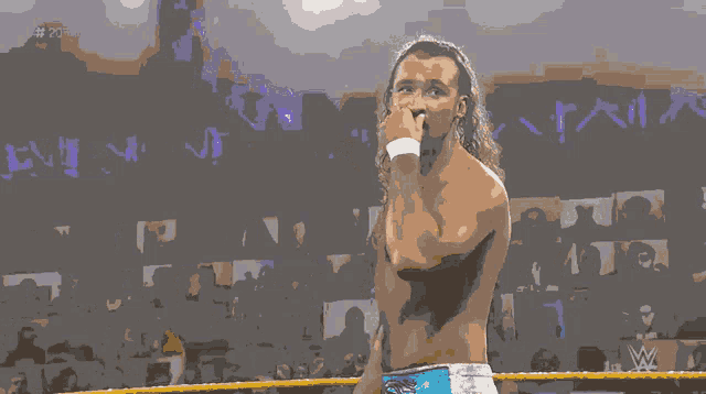 a shirtless wrestler stands in a wrestling ring with the letters w on the bottom