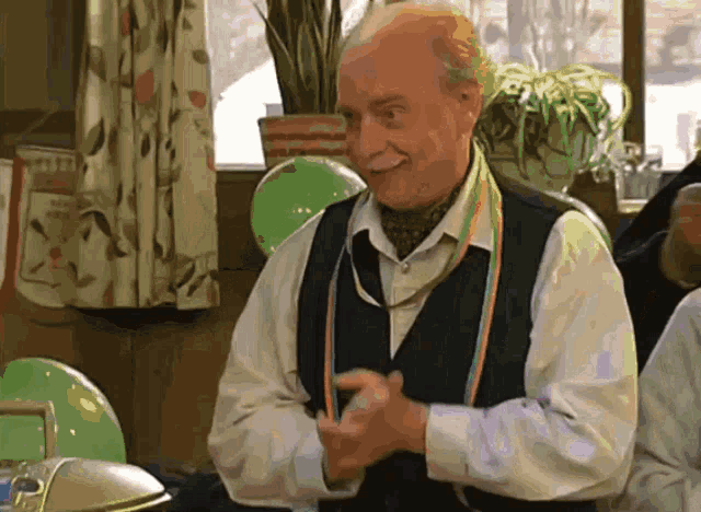 a man wearing a vest and tie is smiling and clapping