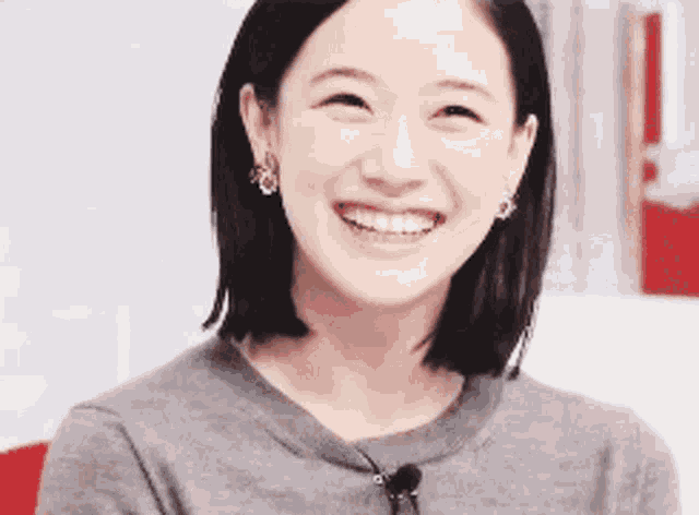a woman is smiling and wearing a grey shirt