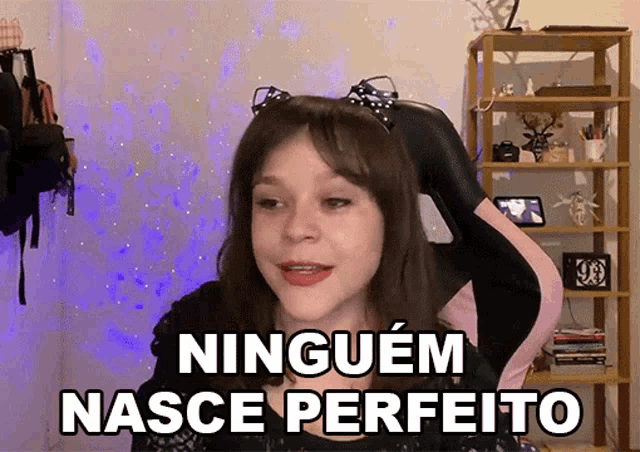 a girl with cat ears is sitting in a chair and says " ninguem nasce perfeito "