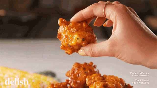 a close up of a person holding a piece of food with the words delish on the bottom