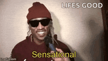 a man wearing sunglasses and a beanie is holding a microphone and saying life is good and sensational