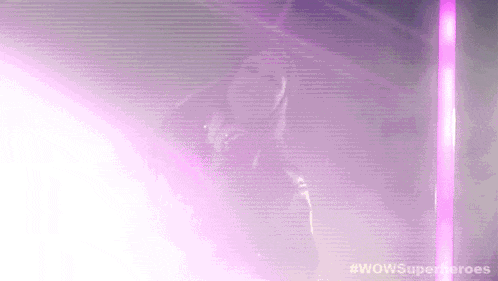 a woman is dancing in a dark room with purple lights .