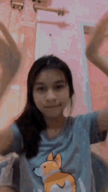 a girl wearing a t-shirt with a dog on it is dancing in a room .
