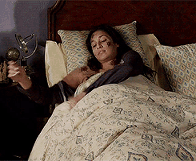 a woman is laying in a bed holding a trophy in her hand