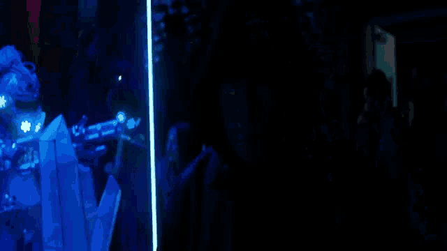 a group of people are standing in a dark room with blue lights