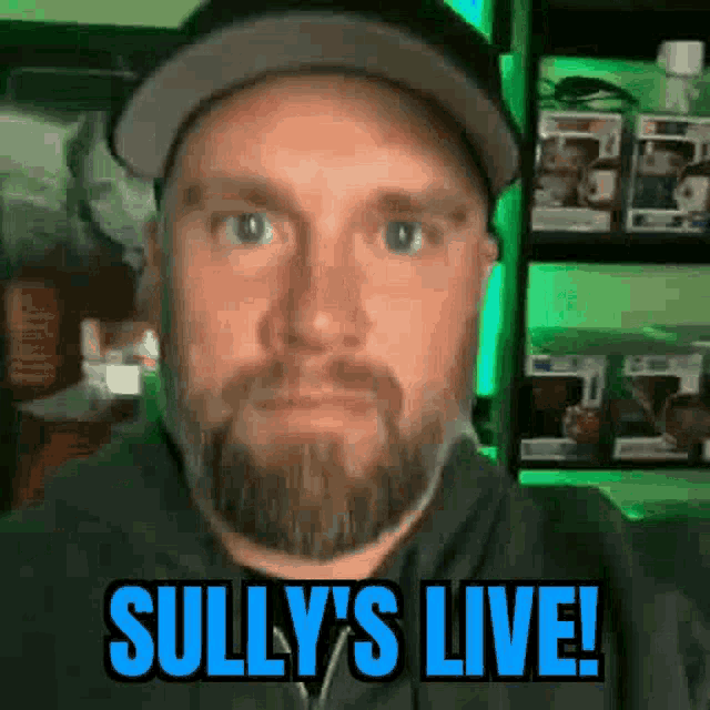a man with a beard is wearing a hat and a hoodie and says sully 's live !