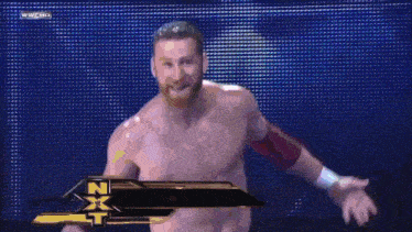 a shirtless wrestler is walking down a wrestling ring with a wwhd logo in the background