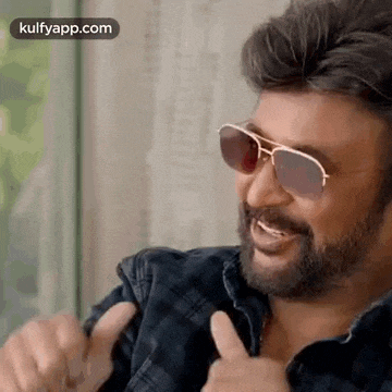 a man with a beard wearing sunglasses and giving a thumbs up .