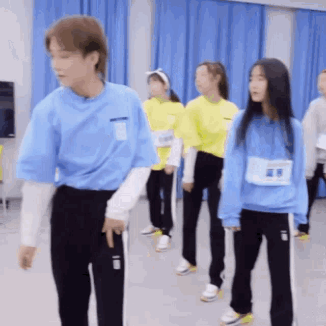 a group of people are standing next to each other in a room with blue curtains .