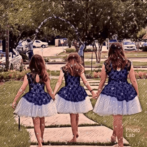 three girls in blue and white dresses are walking down a sidewalk holding hands