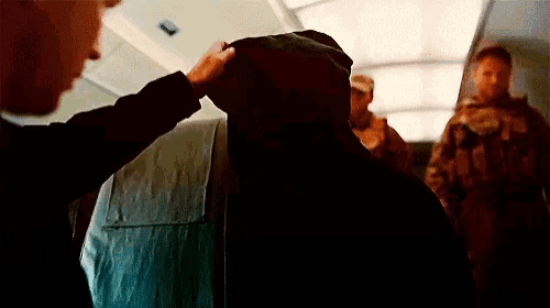 a man in a hooded jacket is being touched by another man on an airplane