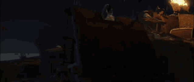 a large fire is burning in a dark room with a ladder in the background .