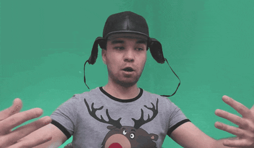 a man wearing a hat and a reindeer shirt reaches out his arms