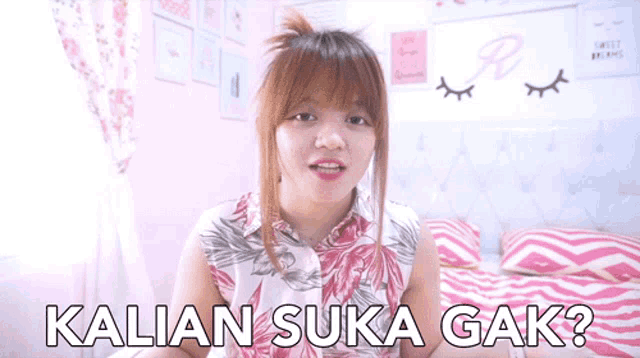a woman is sitting on a bed with the words " kalian suka gak " written on the bottom