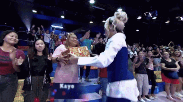 a group of people are applauding a woman in front of a sign that says " kayo "