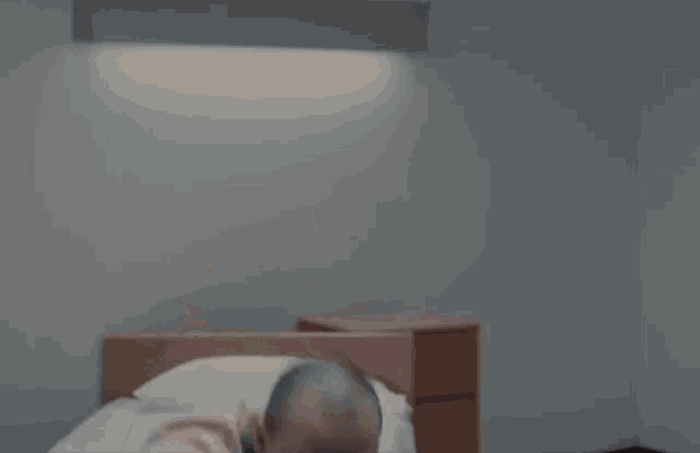 a man in a yellow shirt and blue tie is laying on a bed with his hands outstretched