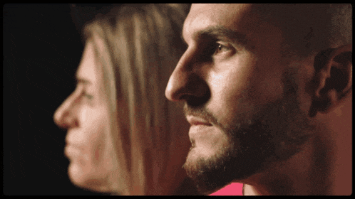 a close up of a man 's face with a woman in the background