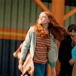 a woman with red hair is holding a skateboard