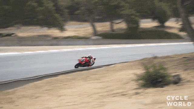 a person riding a motorcycle on a road with the words cycle world visible