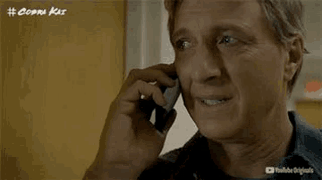 a man is talking on a cell phone while looking at the camera .