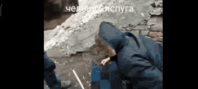 a man in a hooded jacket is smoking a cigarette while another man looks on .