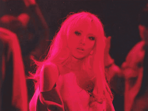 a woman with long blonde hair is standing in a dark room