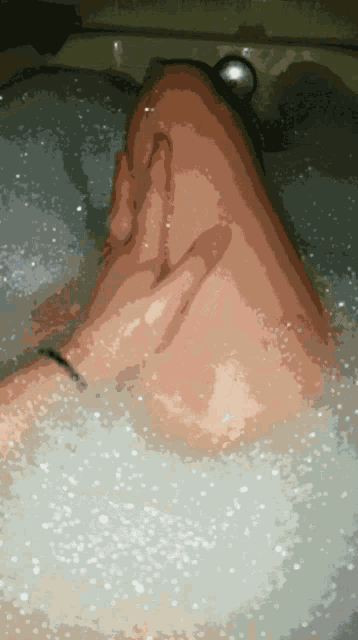 a person laying in a bathtub with bubbles on their feet