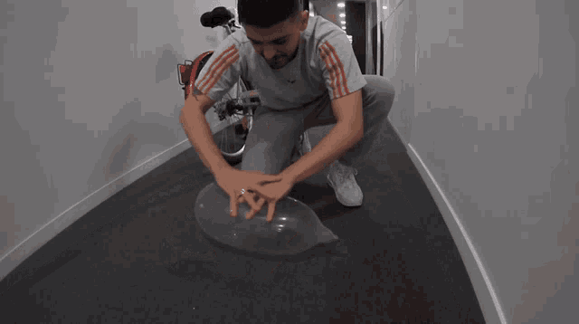 a man is kneeling down on the floor with his hands on a plastic object