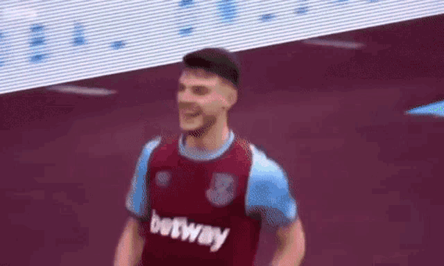 a soccer player wearing a purple and blue jersey is smiling .