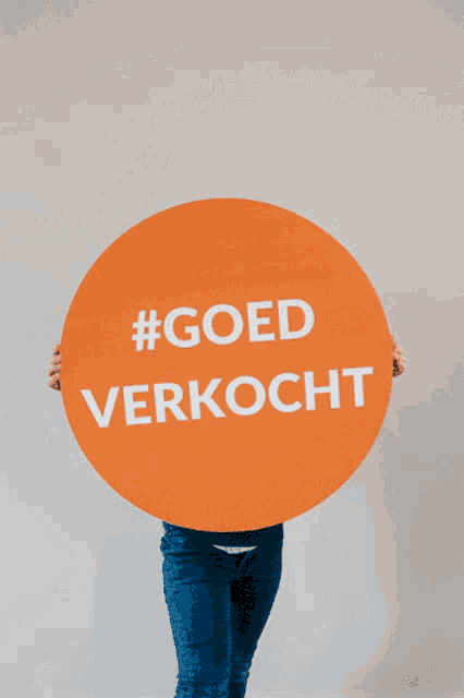 a person holding up a sign that says #goed verkocht