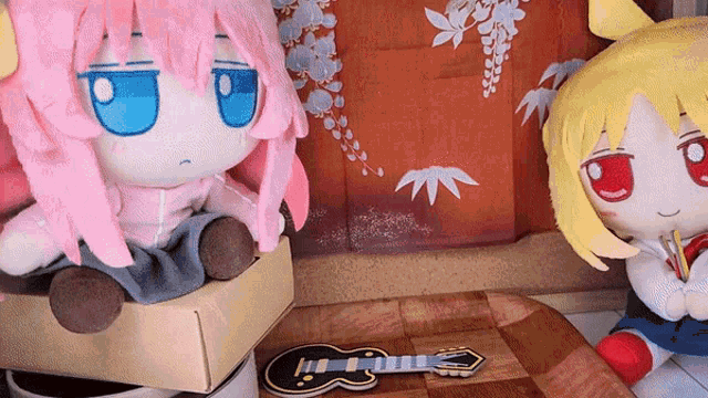 two stuffed dolls are sitting next to each other with one holding a guitar ..