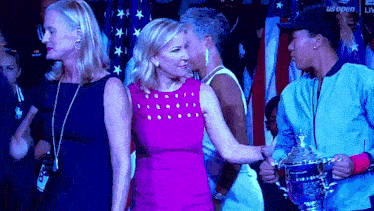 a woman in a pink dress is standing next to a woman holding a trophy