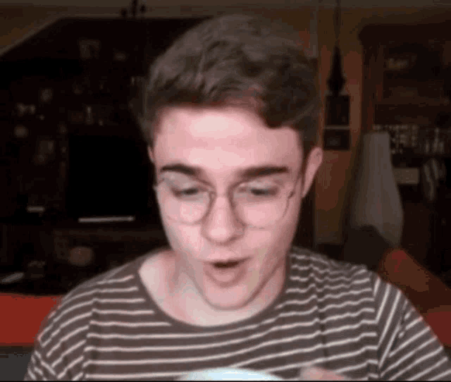 a man wearing glasses and a striped shirt is making a funny face .