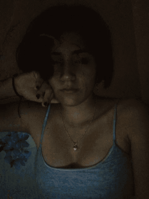 a woman in a blue tank top with a heart necklace