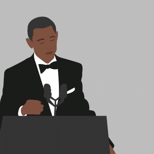 a man in a suit stands at a podium with his hand on his chin