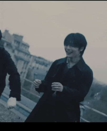 a man in a black coat is smiling while walking with another man